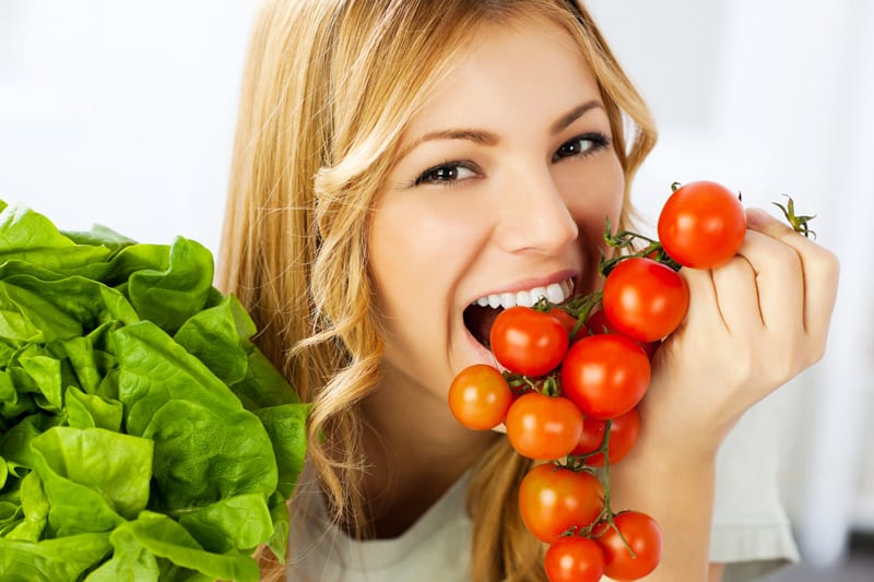 Woman eating cherry tomatoes and lettuce