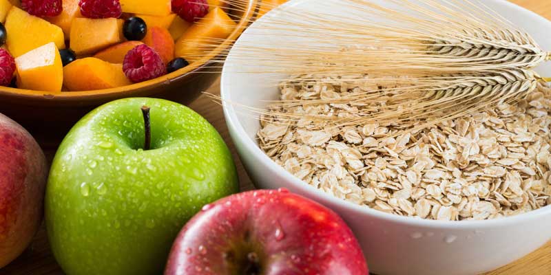 An image of a bowl of oatmeal,fresh fruit, and apples represents fiber