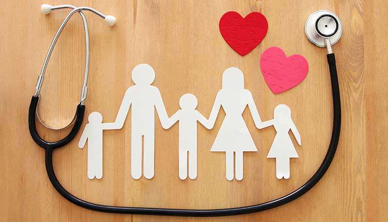 white paper cutout of a family of five flanked by red hearts and a stethoscope