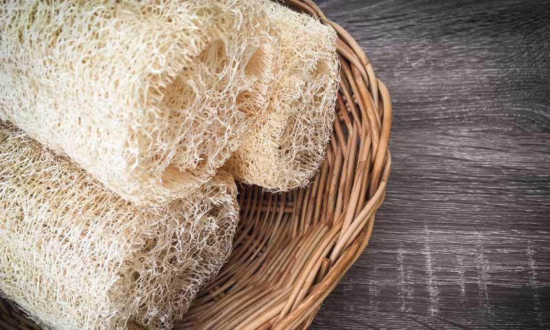 Loofah sponges, used for physical exfoliation, arranged in a wicker basket