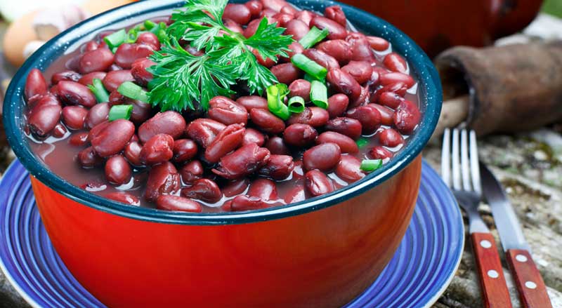 A bowl of cooked kidney beans with parsley and chopped scallions on top