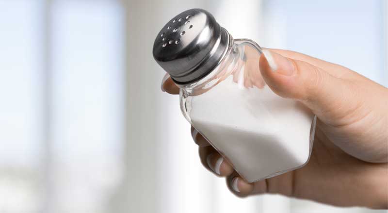 A woman’s hand holding a saltshaker