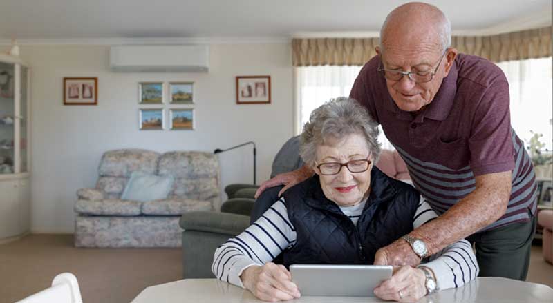 An older couple looking at a computer tablet together at their table